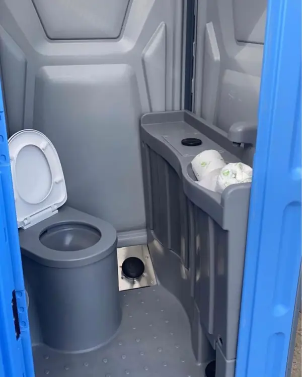 Gray seat and toilet paper holder inside a porta potty