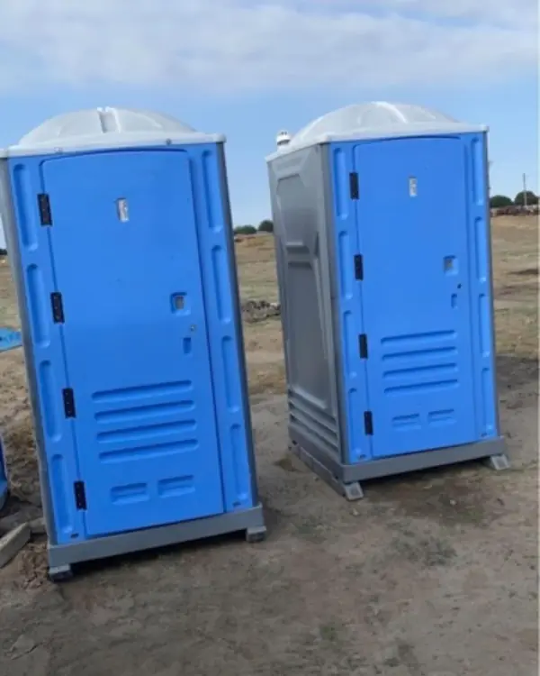 Blue and gray standard porta potties on a dirt lot